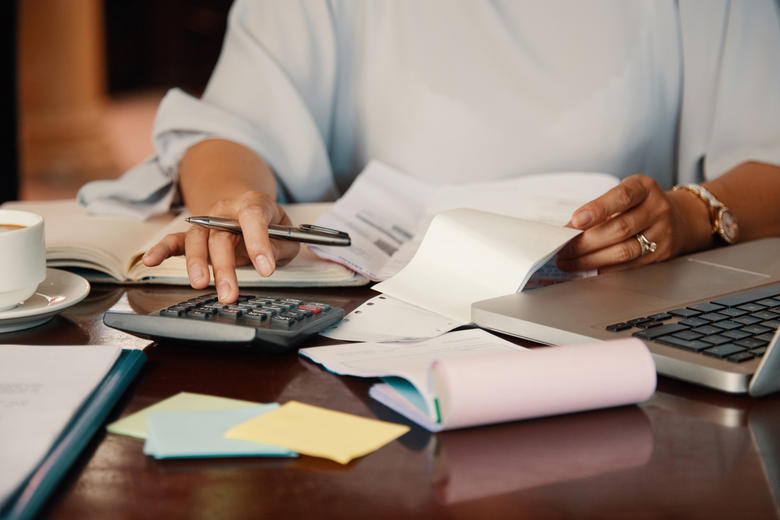 person using a calculator whilst holding finacial papers