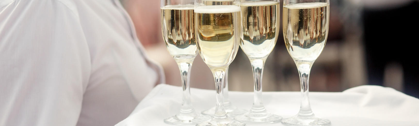Waiter holding a tray of champagne flutes filled with champagne
