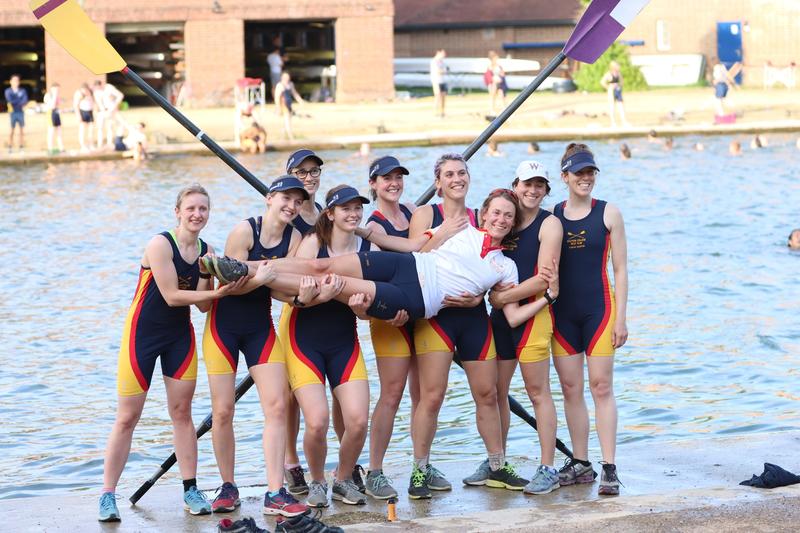Wolfson College Boat Club stood on boat with cox being held by the team celebrating winning at the Head of the River pub
