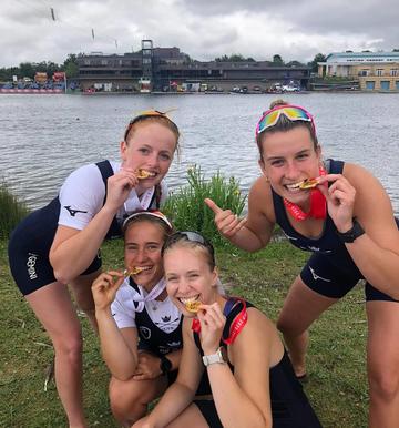 BUCS regatta medal winners, stood holding medals between their teeth