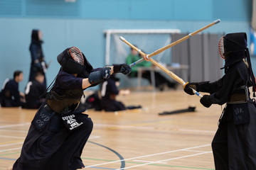 Akari in full kendo gear, wielding a kendo stick against an opponent