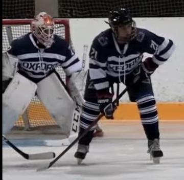 Jake Schneider on ice rink defending in front of goaltender