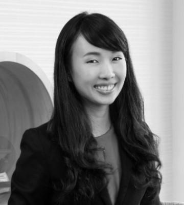 black and white head and shoulders shot of liyan zeng, smiling wearing a business jacket, long black hair.