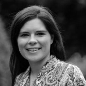 black and white head and shoulders shot of Rebecca Schneider wearing patterned shirt and long black hair.