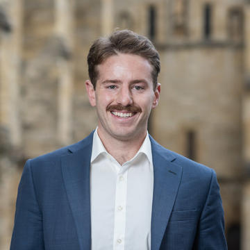 Image of Thomas Monahan standing in front of a University building