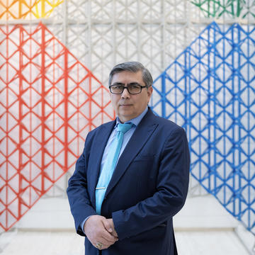 Dr Yahia Baiza standing in front of a colorful net-like art installation