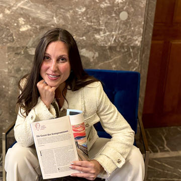 Selena Milanovic sitting on a chair, holding a copy of her published article.