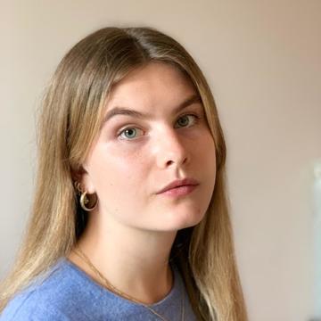 Holly bird headshot, long hair and blue sweater looking to the right.