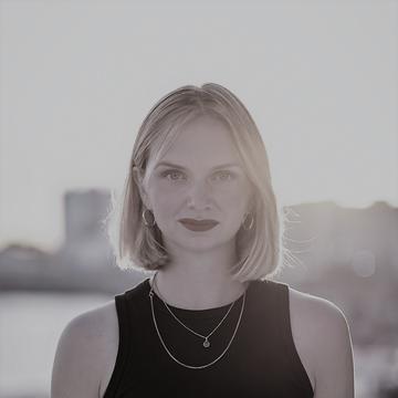 black and white shot of Kristina Lunz head and shoulders in black dress with sun kissed background 