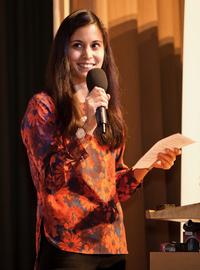 Samantha Vanderslott stood holding a microphone and a piece of paper.