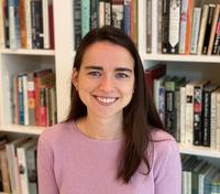 Katherine McCreery head and shoulders wearing pink sweater in front of a bookcase.