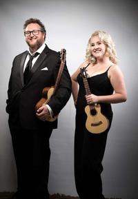male and female both stood smiling with ukuleles wearing formal evening wear.